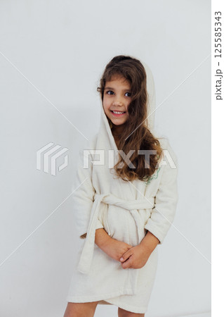 Little girl in bathrobe on white background 125585343