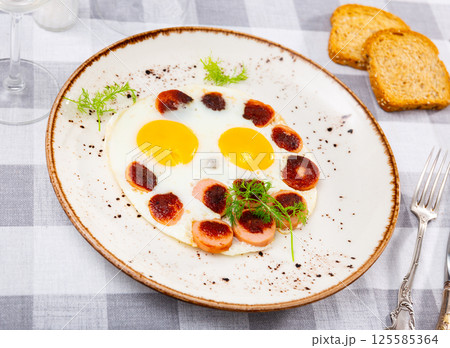 Spicy grilled sausages garnished with scrambled eggs fried close up Spicy grilled sausages garnished with scrambled eggs fried close up 125585364