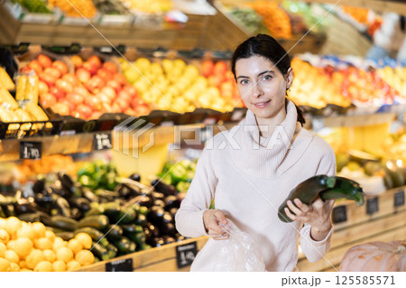 In vegetable store, young woman customer buy ripe eggplant 125585571