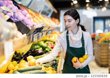 Woman staff with lemon in hands in greengrocery 125585639
