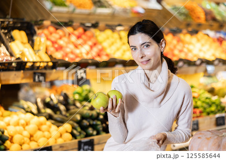 In vegetable store, young woman customer buy apple In vegetable store, young woman customer buy apple 125585644