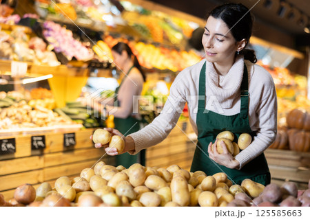 Female employee informs about arrival of ripe potato, advertises product Female employee informs about arrival of ripe potato, advertises product 125585663