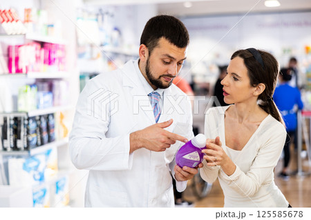 Pharmacist consulting woman buyer about hair care product 125585678