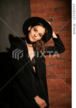 woman in black jacket and hat on dark background woman in black jacket and hat on dark background 125585737