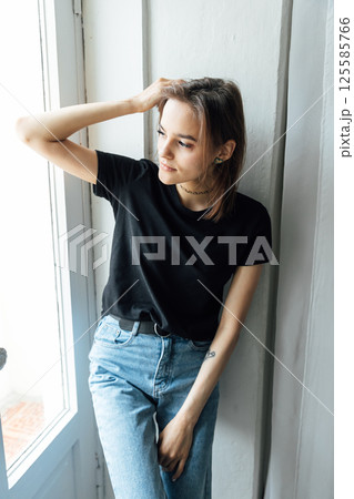 brunette woman posing in photo studio and smiling while sitting on chair 125585766
