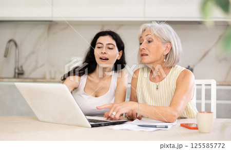 Mature woman consulting with female real estate agent in home Mature woman consulting with female real estate agent in home 125585772