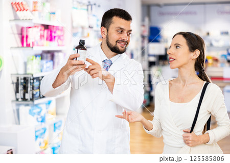 Pharmacist advises customer in pharmacy, offers medicine for body care Pharmacist advises customer in pharmacy, offers medicine for body care 125585806