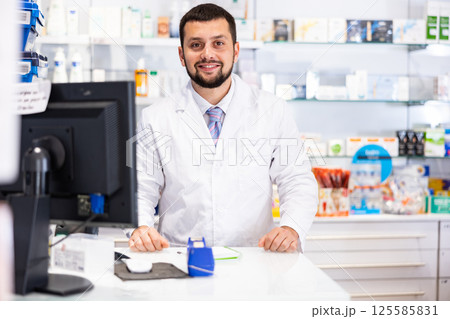 Friendly male pharmacist working at cash desk Friendly male pharmacist working at cash desk 125585831