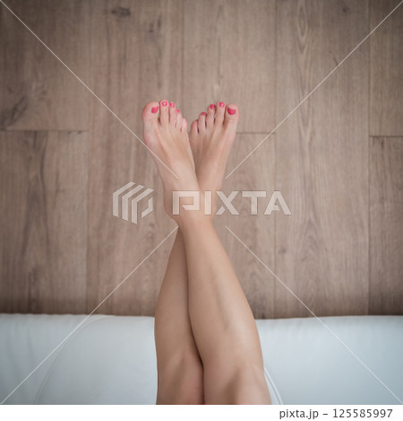 Close-up of a young woman's legs on the bed. Close-up of a young woman's legs on the bed. 125585997