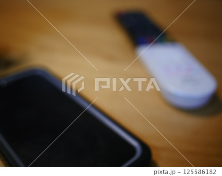 テーブルに置かれたスマートフォン パソコンのキーボードとリモコン コピースペース 自宅の何気ない景色 テーブルに置かれたスマートフォン パソコンのキーボードとリモコン コピースペース 自宅の何気ない景色 125586182