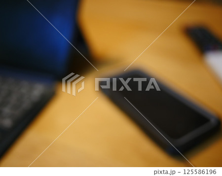 テーブルに置かれたスマートフォン　パソコンのキーボードとリモコン　コピースペース　自宅の何気ない景色 125586196