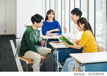 学校の教室で休み時間に談笑をする男女学生 学校の教室で休み時間に談笑をする男女学生 125586391