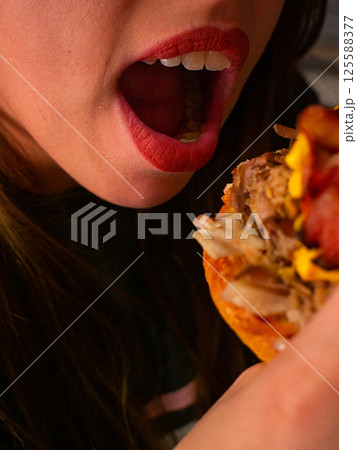An Excited Bite of a Delicious and Flavorful Burger with Colorful and Tempting Toppings An Excited Bite of a Delicious and Flavorful Burger with Colorful and Tempting Toppings 125588377