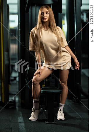 confident individual showcases strength and style while posing in contemporary gym. environment features workout equipment and sleek design emphasizing fitness and wellness. confident individual showcases strength and style while posing in contemporary gym. environment features workout equipment and sleek design emphasizing fitness and wellness. 125591118