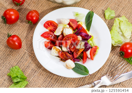 Classic Italian caprese salad for dinner, on a dark rustic table 125591454