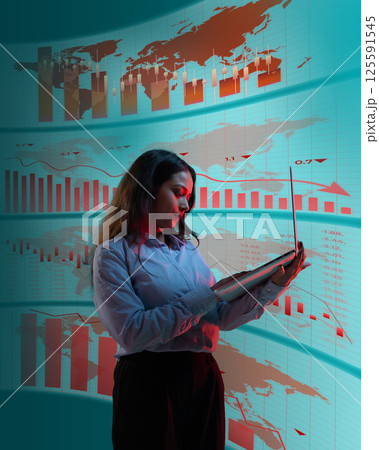 Woman with laptop analyzing economic charts on global screen with red and blue highlights. Woman with laptop analyzing economic charts on global screen with red and blue highlights. 125591545