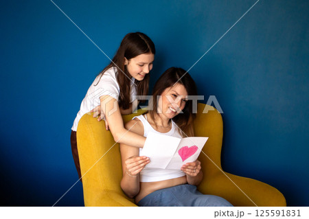 Happy mother's day. Child daughter congratulates moms and gives her gift box and handmade greeting card. Happy mother's day. Child daughter congratulates moms and gives her gift box and handmade greeting card. 125591831