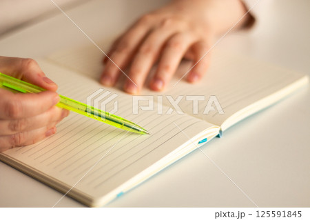 Warm toned image of hand writing personal thoughts in diary. Blurred background for cozy atmosphere. 125591845