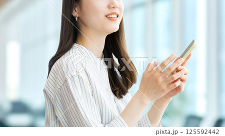 スマートフォンを使う笑顔の女性・ビジネスウーマン 125592442