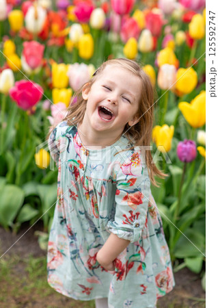 Happy girl laughs in a park with the tulips field 125592747