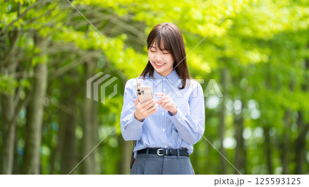 遊歩道でスマートフォンを使う笑顔の女性・ビジネスウーマン 遊歩道でスマートフォンを使う笑顔の女性・ビジネスウーマン 125593125
