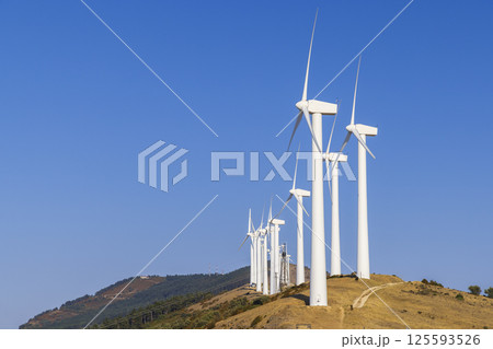 Wind turbines generating clean energy on a hilltop under a clear blue sky Wind turbines generating clean energy on a hilltop under a clear blue sky 125593526
