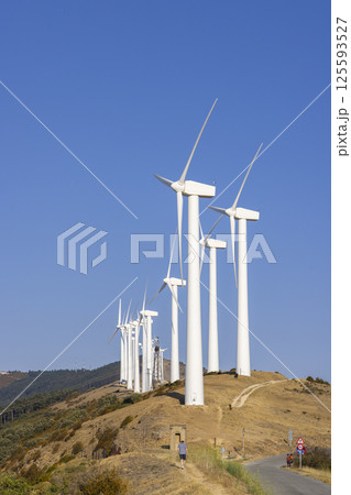 Wind turbines generating clean energy on a hilltop under a clear blue sky 125593527