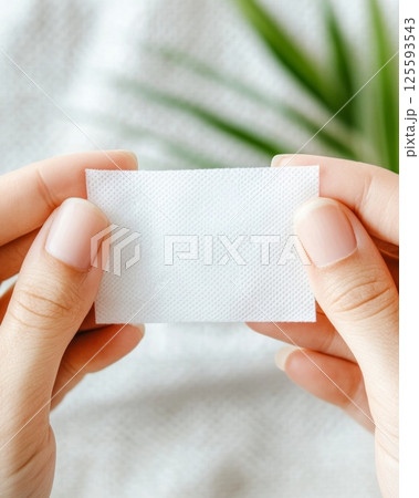 Hands holding a transparent adhesive bandage over a small wound in a bright home environment 125593543