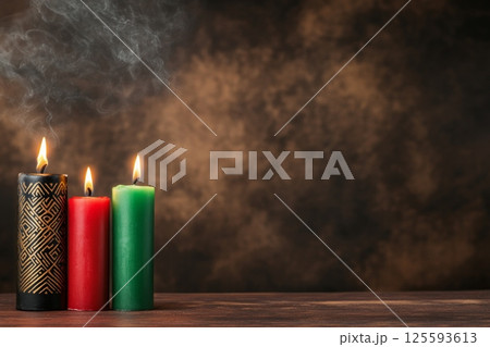 Warmly lit Kinara with red, green, and black candles adorned with African patterns against a dark background 125593613