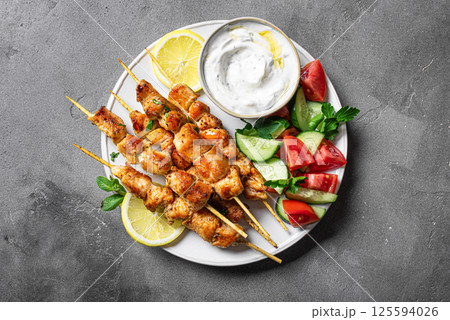 Mediterranean lunch with souvlaki skewers, yogurt sauce and vegetables 125594026