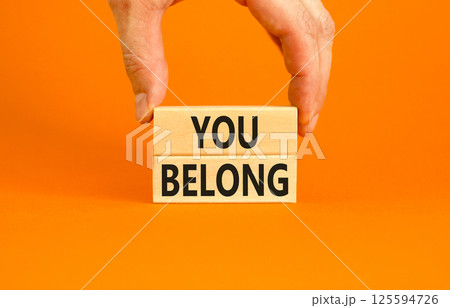Belonging and you belong symbol. Concept words You belong on beautiful wooden blocks. Beautiful orange background. Businessman hand. Business belonging and you belong concept. Copy space. Belonging and you belong symbol. Concept words You belong on beautiful wooden blocks. Beautiful orange background. Businessman hand. Business belonging and you belong concept. Copy space. 125594726