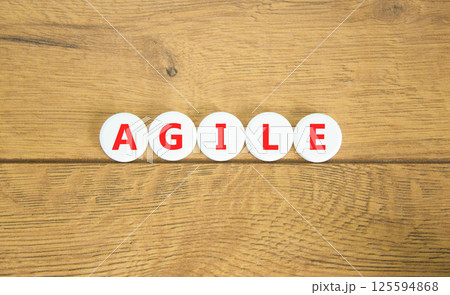 Agile symbol. Concept word Agile on beautiful white pills circles. Beautiful wooden table wooden background. Business flexible and agile concept. Copy space. 125594868