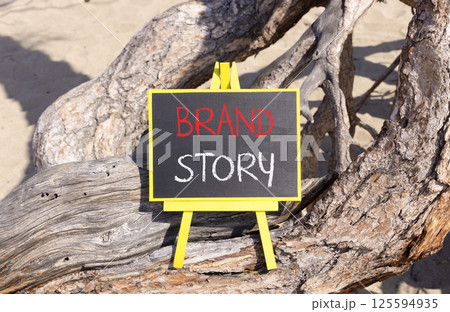Brand story branding symbol. Concept words Brand story on beautiful yellow chalk blackboard. Beautiful old tree and sand background. Business brand story branding concept. Copy space. Brand story branding symbol. Concept words Brand story on beautiful yellow chalk blackboard. Beautiful old tree and sand background. Business brand story branding concept. Copy space. 125594935