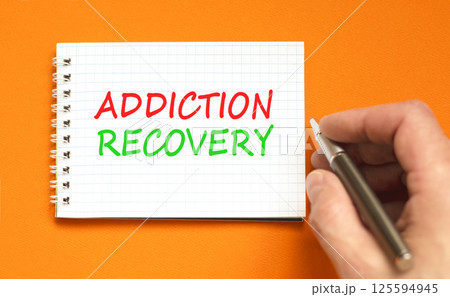 Addiction recovery symbol. Concept words Addiction recovery on beautiful white note. Psychologist hand. Beautiful orange table orange background. Psychology addiction recovery concept. Copy space. Addiction recovery symbol. Concept words Addiction recovery on beautiful white note. Psychologist hand. Beautiful orange table orange background. Psychology addiction recovery concept. Copy space. 125594945