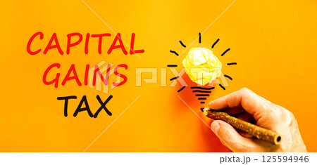 Capital gains tax symbol. Concept words Capital gains tax on beautiful orange paper. Beautiful orange background. Businessman hand with pencil. Business and capital gains tax concept. Copy space. Capital gains tax symbol. Concept words Capital gains tax on beautiful orange paper. Beautiful orange background. Businessman hand with pencil. Business and capital gains tax concept. Copy space. 125594946