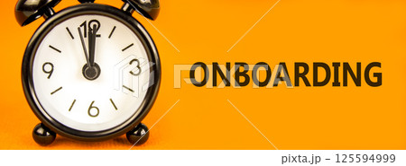 Onboarding success symbol. Concept word Onboarding on beautiful orange paper. Beautiful orange paper background. Black alarm clock. Business onboarding success concept. Copy space. 125594999