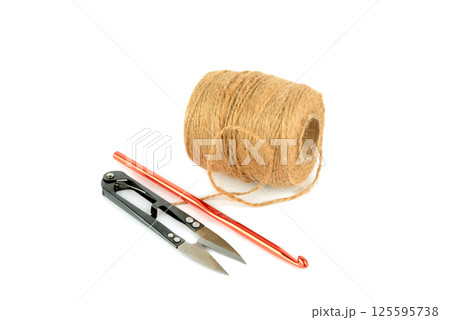 Ball of hemp rope, crochet hook and scissors isolated on white. Ball of hemp rope, crochet hook and scissors isolated on white. 125595738