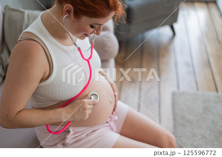 A pregnant woman listens to her baby's pulse using a phonendoscope. A pregnant woman listens to her baby's pulse using a phonendoscope. 125596772