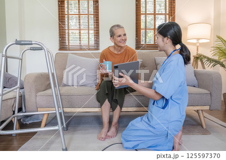 Young Nurse Offering Health Care Advice to Elderly Woman in a Cozy Living Room Setting 125597370