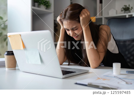 Young Businesswoman Experiencing Stress and Fatigue at Work in a Modern Office Environment 125597485
