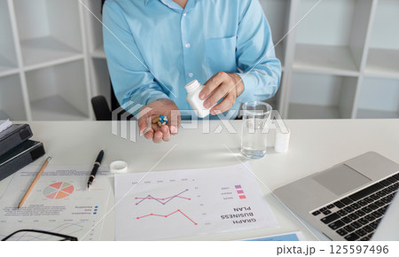 Office Worker Feeling Unwell with Cold Symptoms at Desk with Medication and Business Documents in Modern Workspace Office Worker Feeling Unwell with Cold Symptoms at Desk with Medication and Business Documents in Modern Workspace 125597496