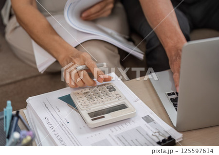 Elderly Couple Managing Family Finances with Calculator and Laptop at Home 125597614