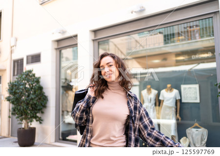 Stylish woman with shopping bags walking outside a fashion boutique, enjoying a shopping day in the city. Stylish woman with shopping bags walking outside a fashion boutique, enjoying a shopping day in the city. 125597769