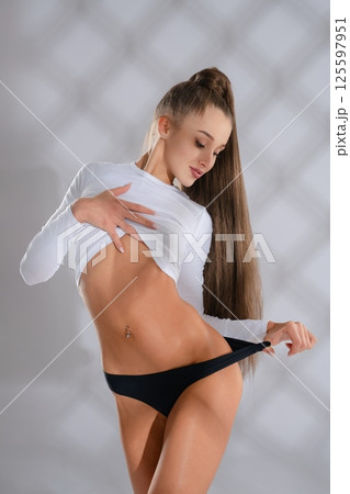 Sporty woman showcasing fitness in a sleek outfit during a studio session Sporty woman showcasing fitness in a sleek outfit during a studio session 125597951