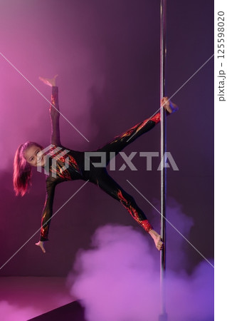 Girl performs pole dance routine in stylish costume with colorful lights 125598020