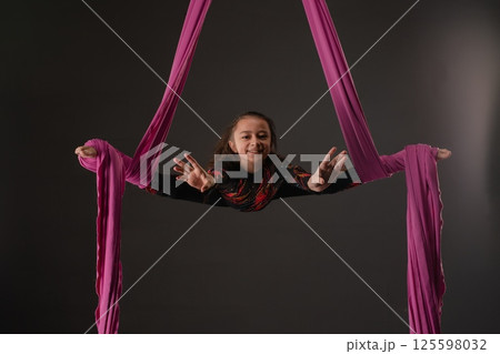 Girl performing aerial sport with pink fabric during indoor session 125598032