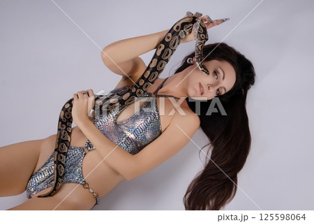 Sensuous woman poses with a snake in alluring lingerie setting Sensuous woman poses with a snake in alluring lingerie setting 125598064