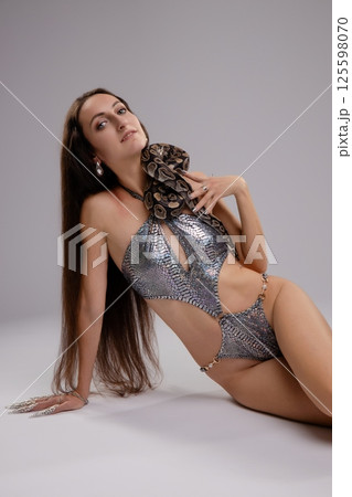 Woman posing in lingerie with a snake against a grey background Woman posing in lingerie with a snake against a grey background 125598070
