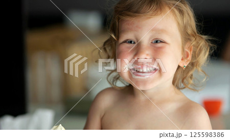 Cheerful preschooler girl enjoys ice cream with big smile Cheerful preschooler girl enjoys ice cream with big smile 125598386