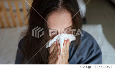 Sick woman blowing nose in hotel room 125598391